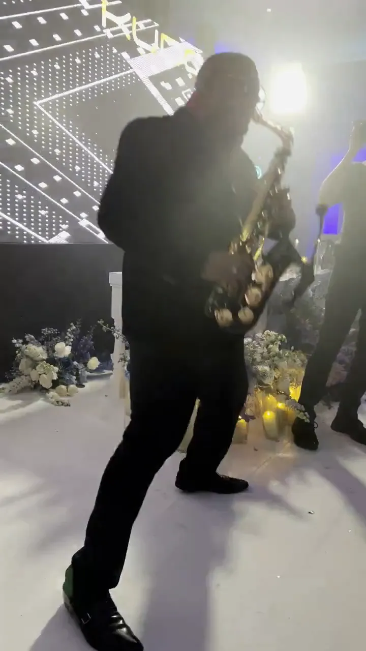 Saxophonist playing a high energy party set on a lit dancefloor