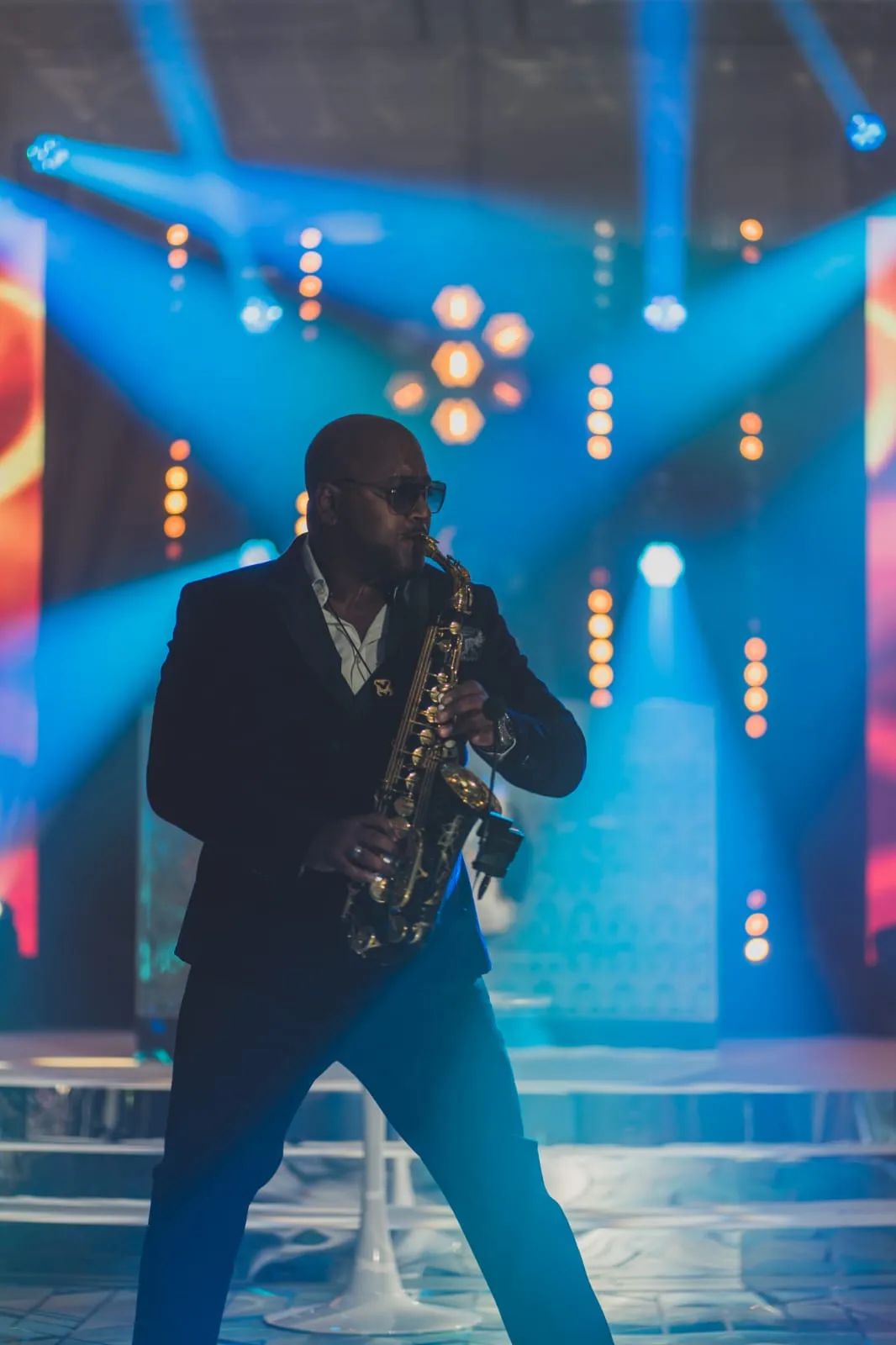 Saxophonist performing under blue stage lights