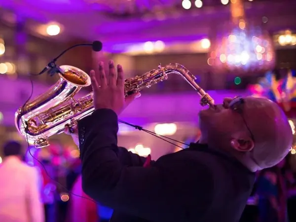 Saxophonist playing at a wedding reception with purple lighting