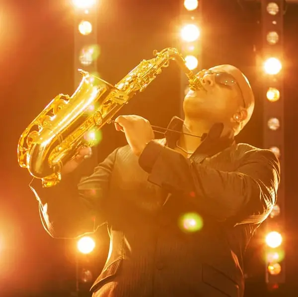Saxophonist playing a solo under warm stage lights