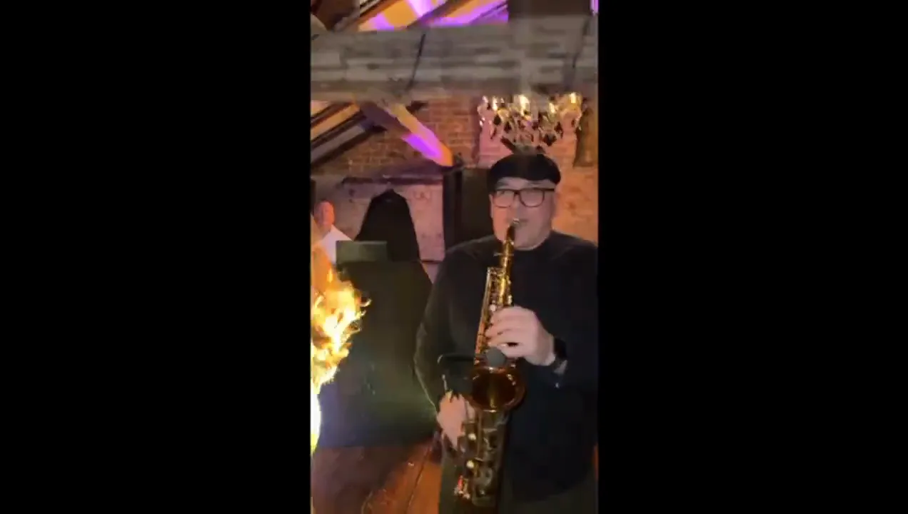 Saxophonist playing among guests at a party
