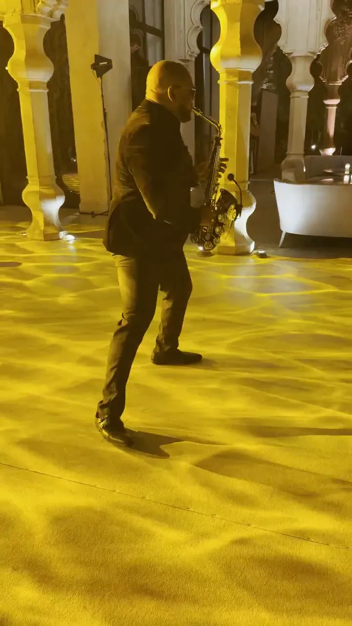 Saxophonist performing a dinner set in a gold-lit venue