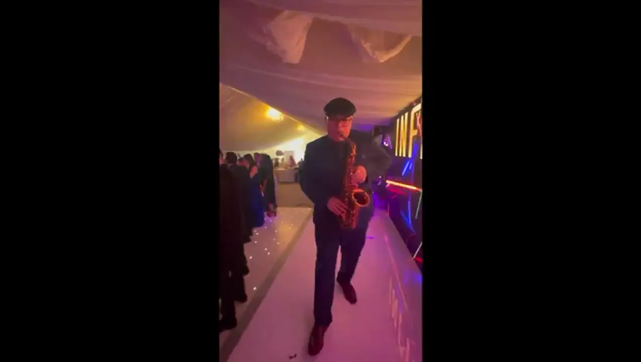 Saxophonist playing to a packed dancefloor at a wedding party