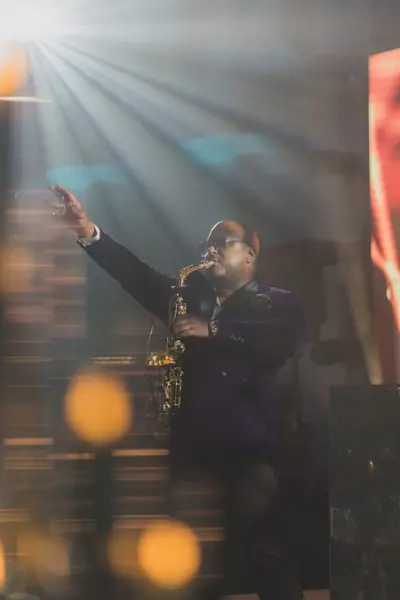 Saxophonist performing on stage in a beam of light