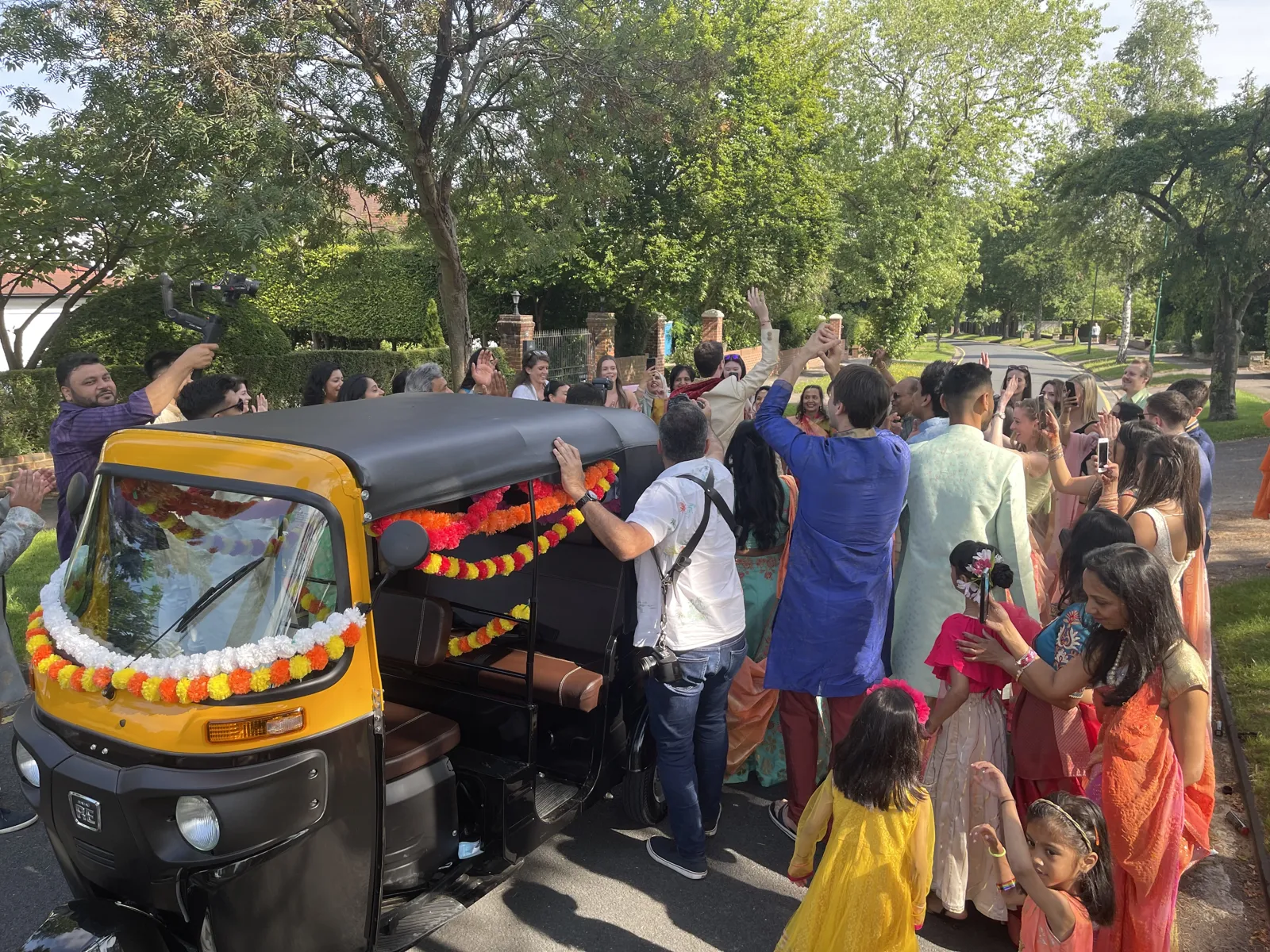 Wedding guests gathered around a decorated tuk tuk