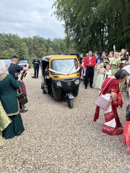A tuk tuk arriving with guests lining the drive