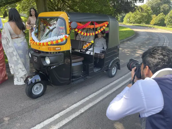 Photographer capturing a couple in a garlanded tuk tuk