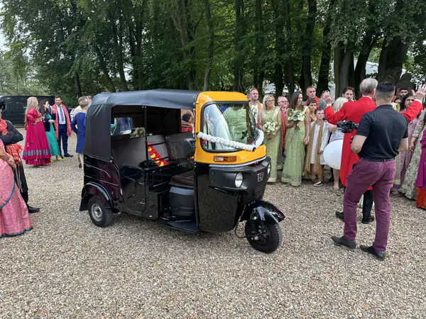 Guests gathering round a tuk tuk at a wedding