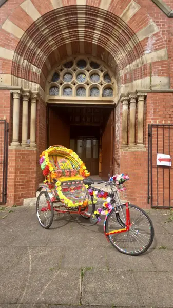 A colourful decorated cycle rickshaw outside an arched doorway