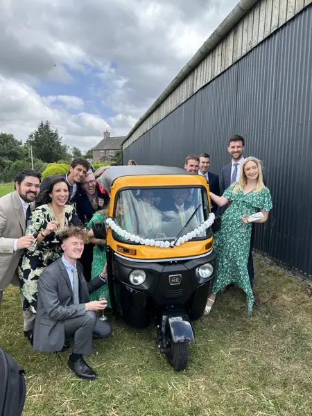 Wedding guests posing around a tuk tuk outdoors