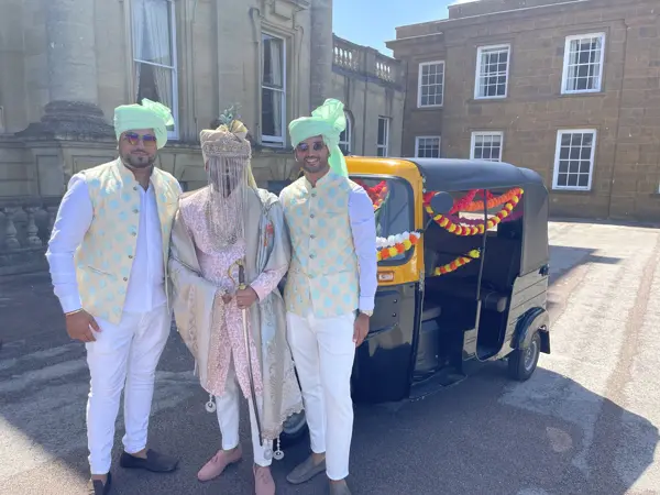 Groom and family posing beside a decorated tuk tuk