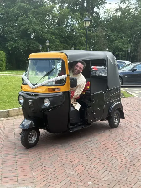 Groom sitting in a tuk tuk with white ribbons