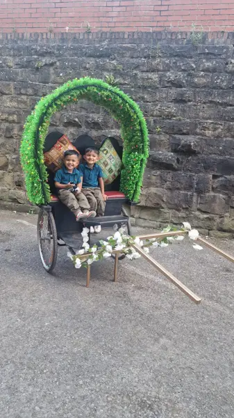 Guests seated in a cycle rickshaw with a floral arch