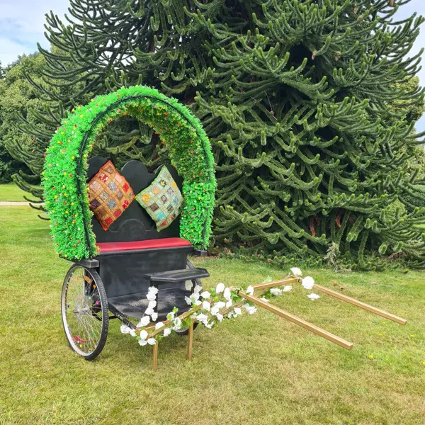A cycle rickshaw with a green floral arch and cushions