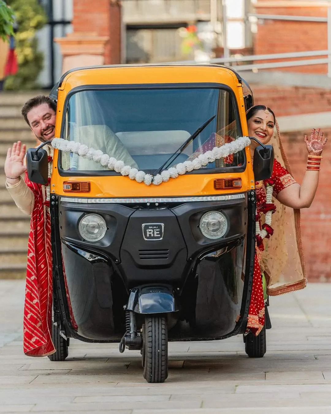 Couple posing either side of a tuk tuk decorated with flowers