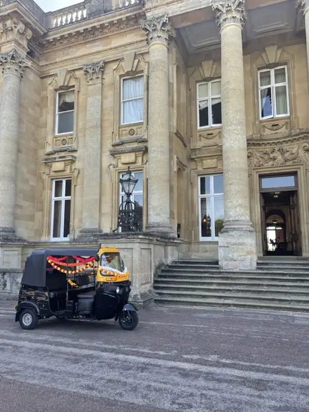 Decorated tuk tuk outside a stately home