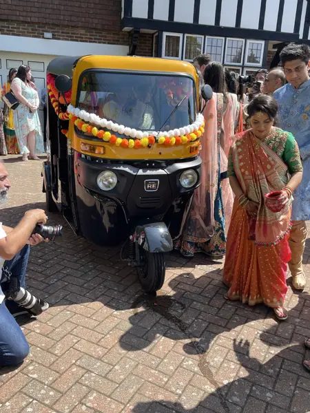 Family members around a tuk tuk decorated with marigolds