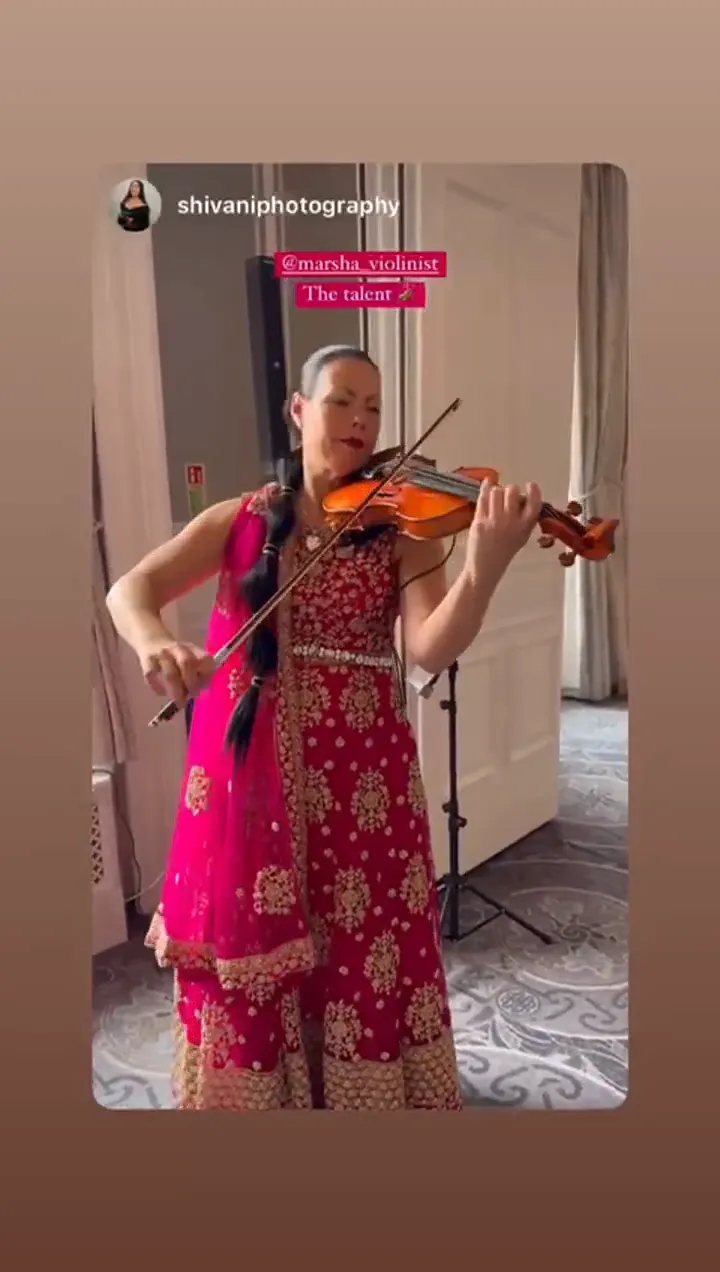 Violinist in a pink lehenga playing her violin
