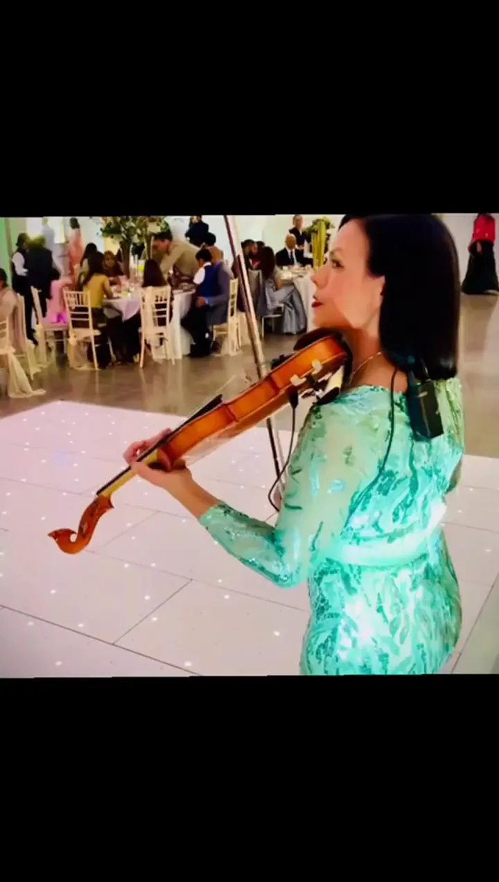 Violinist in a green outfit playing at a reception