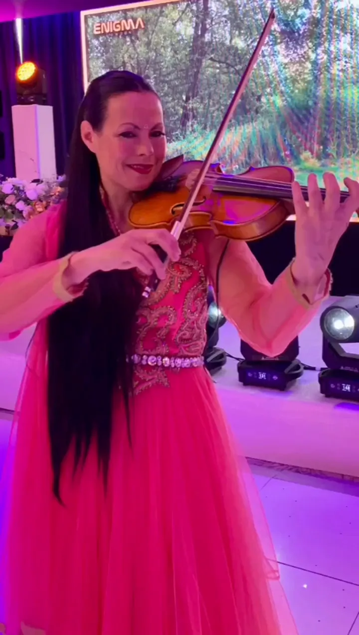 Violinist in a pink gown playing at an evening reception