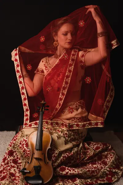 Violinist in a red lehenga and dupatta with her violin