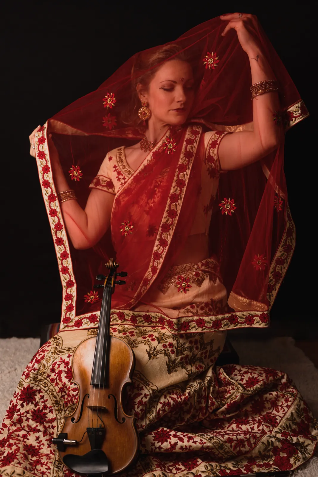 Violinist in a red lehenga and dupatta with her violin