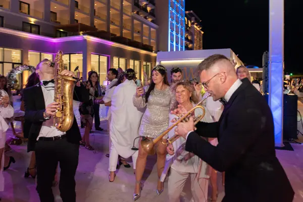 Sax and trumpet players dancing among wedding guests