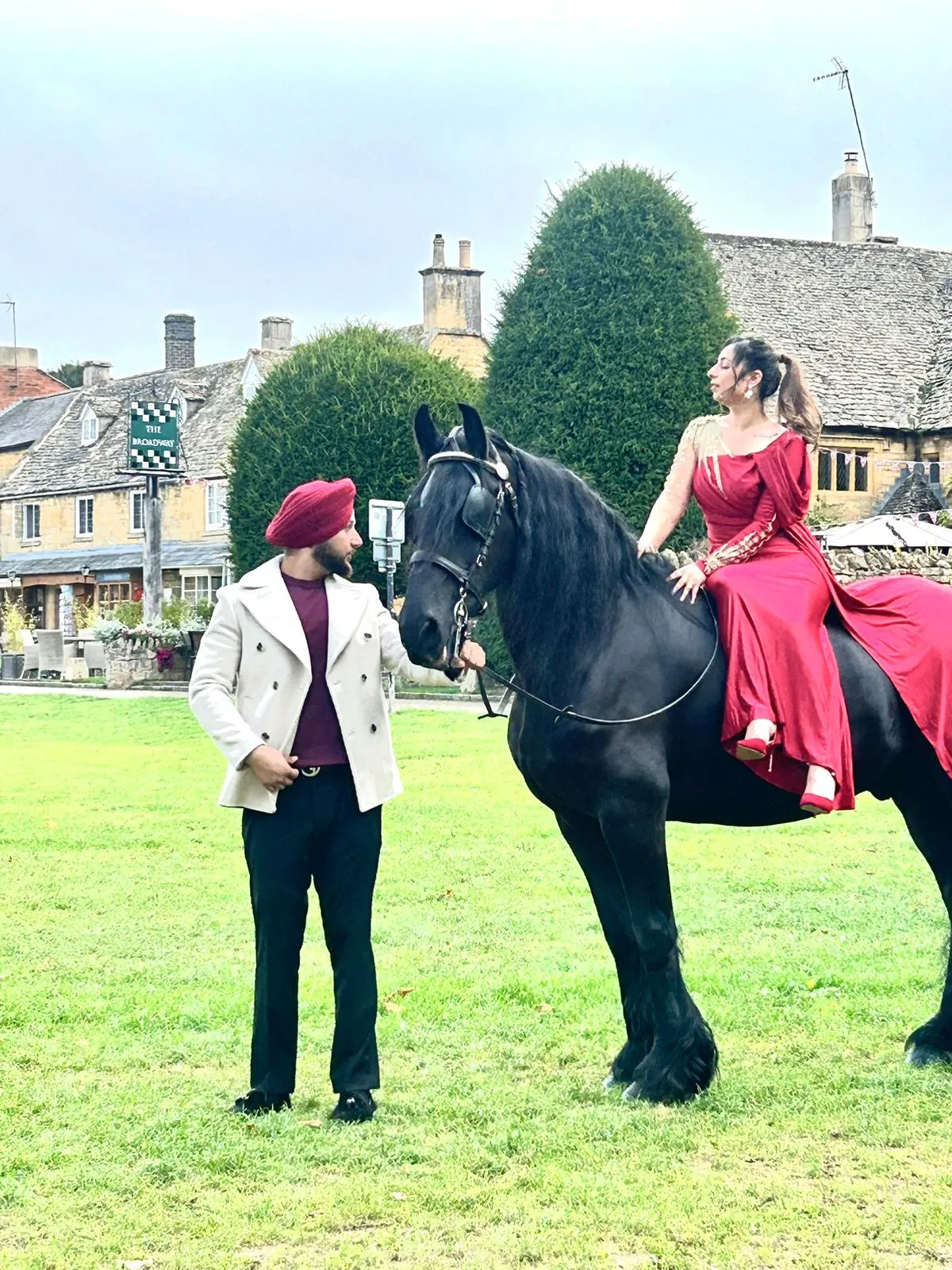 Black horse with a bride in red and a groom for a photo shoot