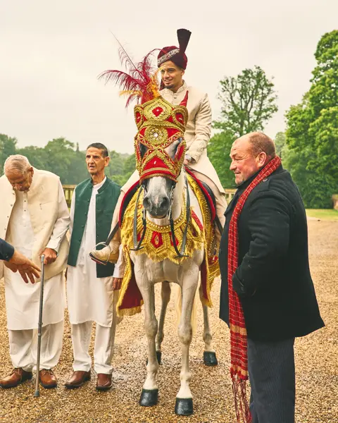 White wedding horse dressed in red and gold with a feathered headpiece