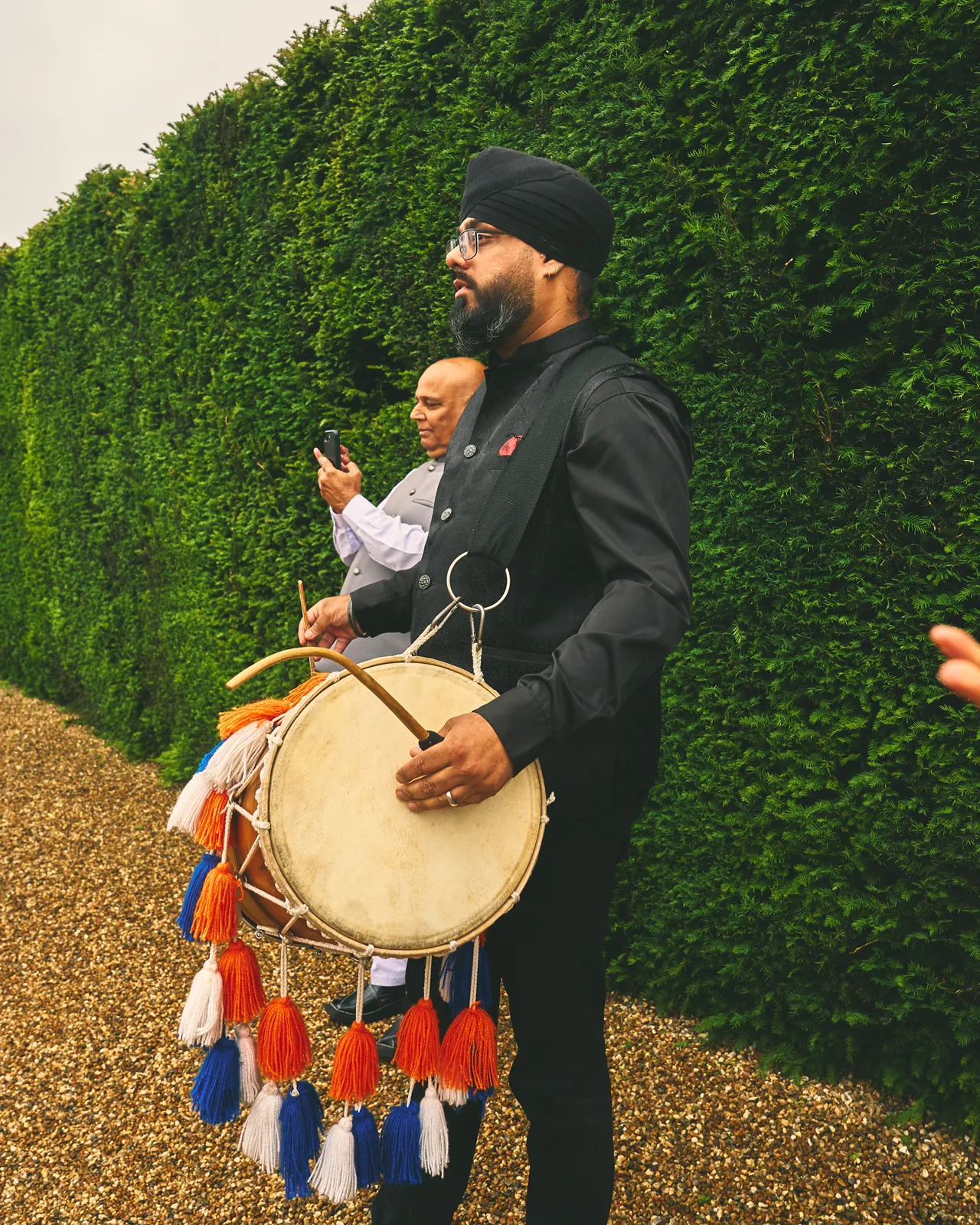 Dhol player in black leading a baraat
